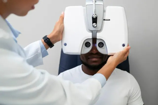 A man is pictured getting his eyes tested by a doctor in a white coat