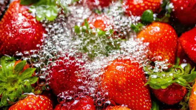 Red strawberries being washed in water