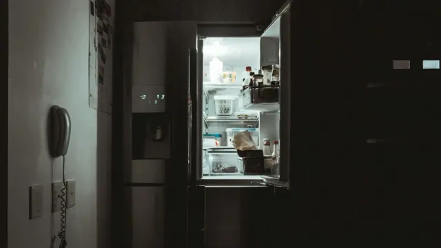 A fridge illuminated at night in a dark kitchen