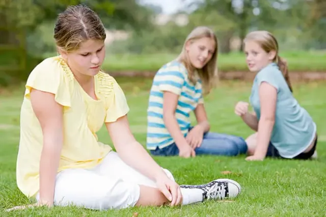 A young girl sitting apart from two others, clearly talking about her