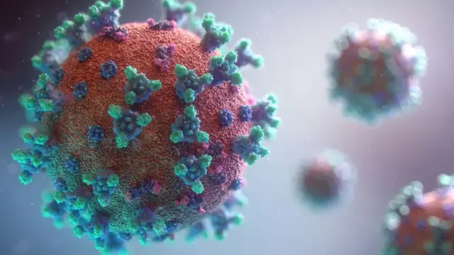 A rendering of a COVID-19 virus in red, blue, and green.