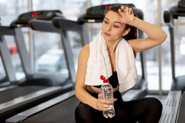 A woman takes a break to drink water while exercising