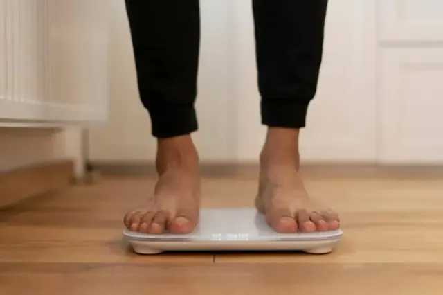 A photograph of a faceless person standing on a scale