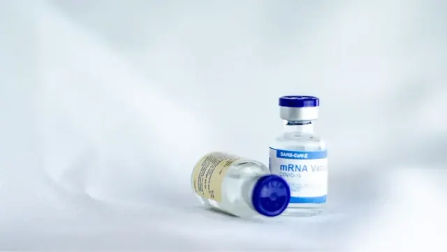Two COVID-19 vaccine bottles in white and blue on a white surface.