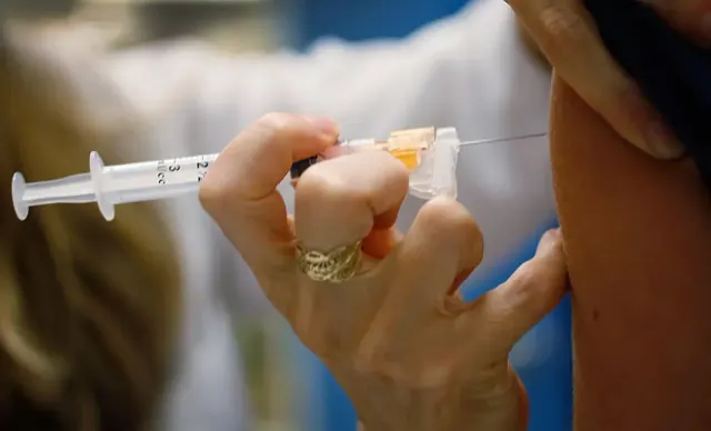 A doctor injects the HPV vaccine into a woman’s arm