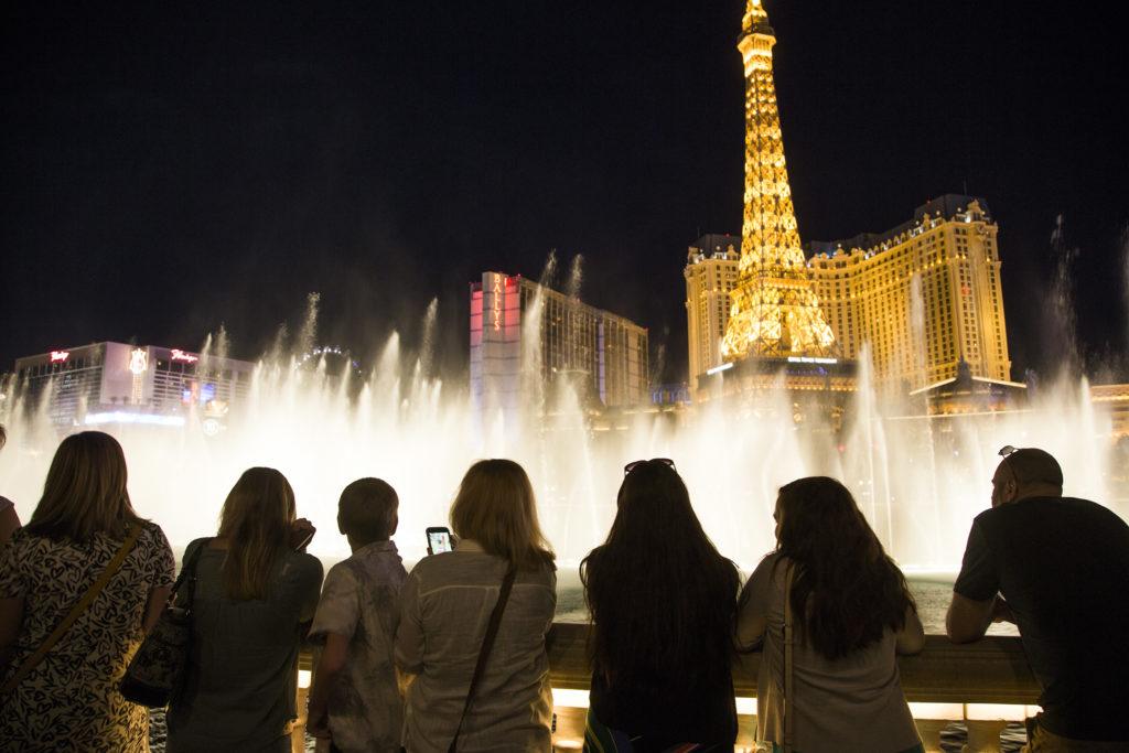 A crowd watching fountains near illuminated hotels; archive photograph.