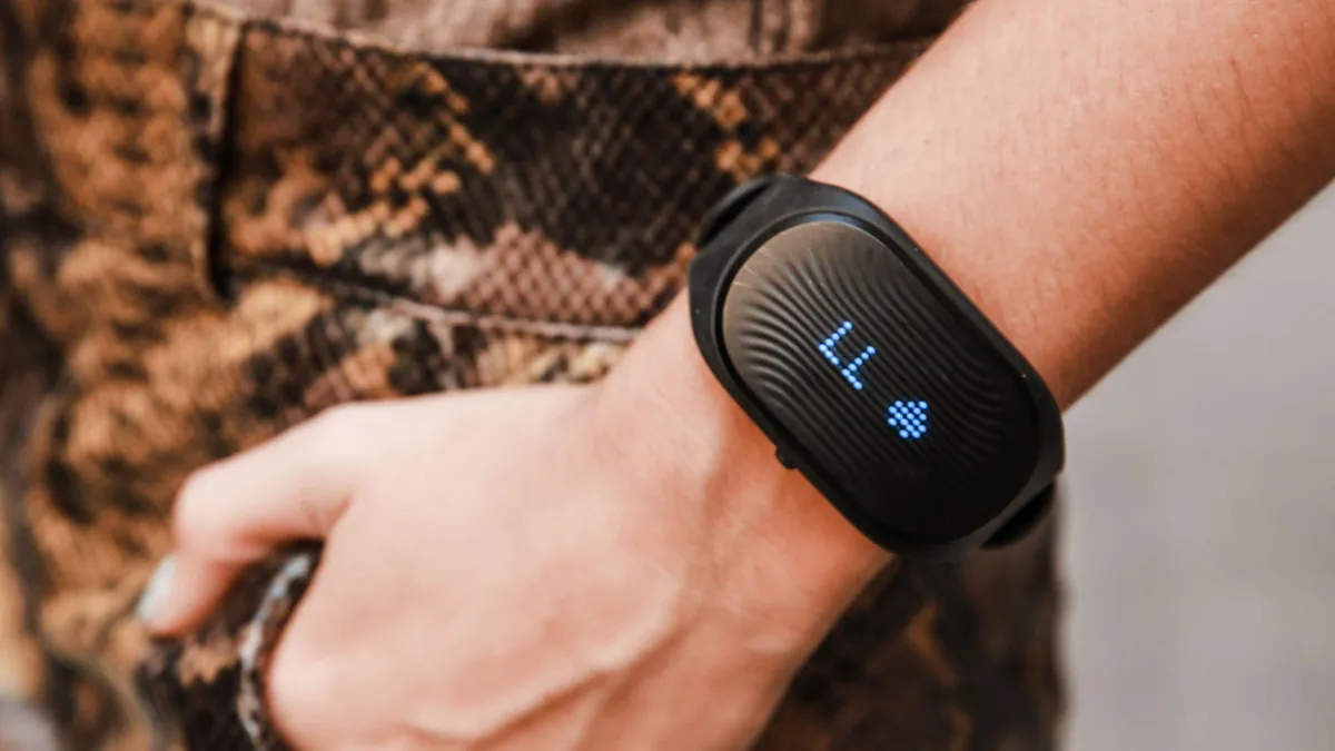 A close-up image of a person's wrist wearing a black fitness tracker with a lit display