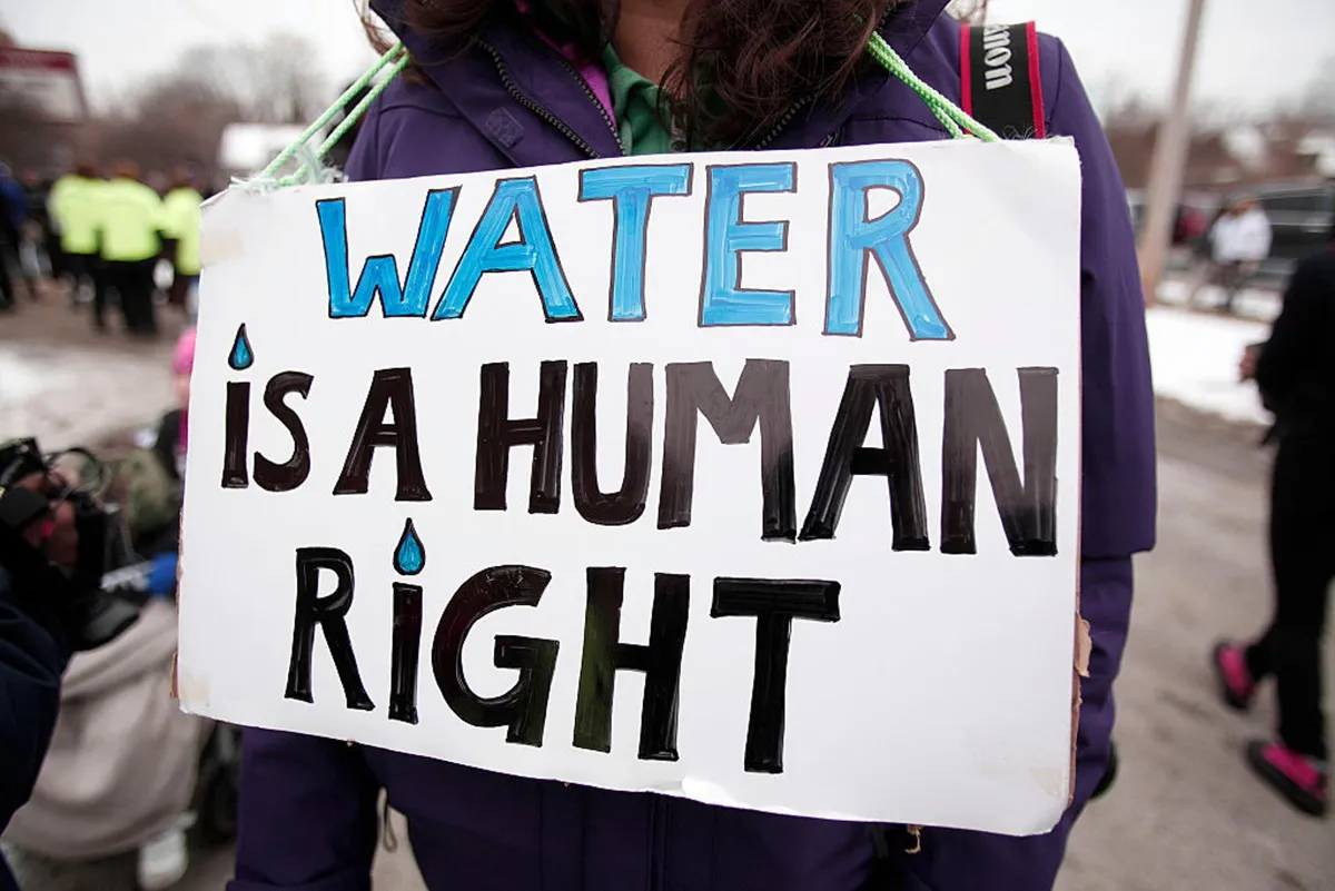 A person holds a sign at a protest that reads “Water Is a Human Right”