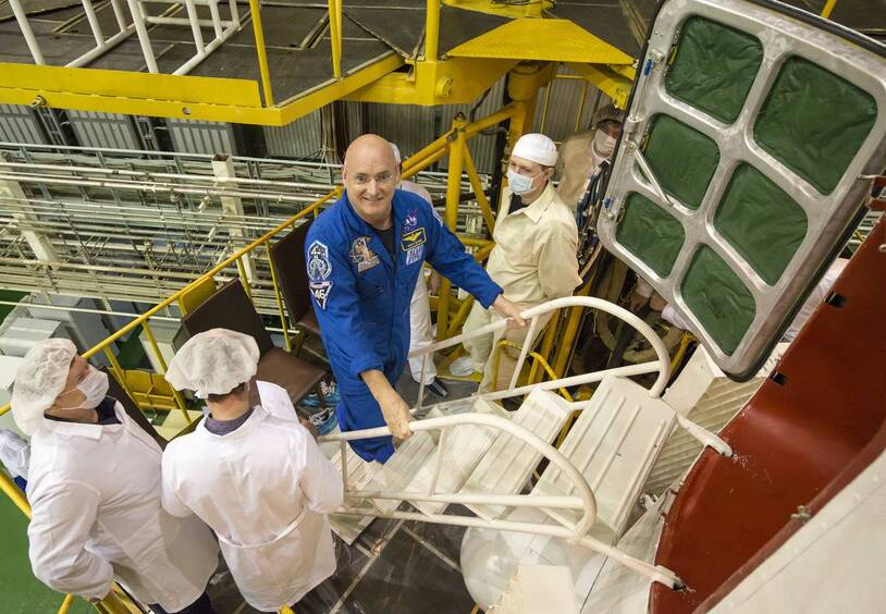 Personnel assisting an astronaut at a spacecraft capsule