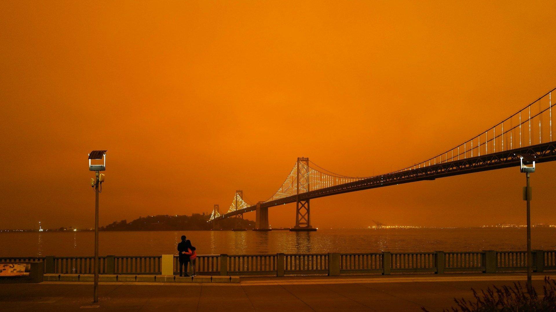 A bridge under orange skies; illustrative archive photograph, not a newly reported wildfire.