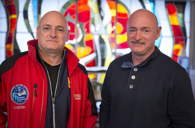 Scott and Mark Kelly standing together in red and blue shirts