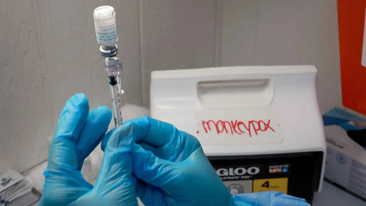 gloved hands hold mpox vaccine and syringe