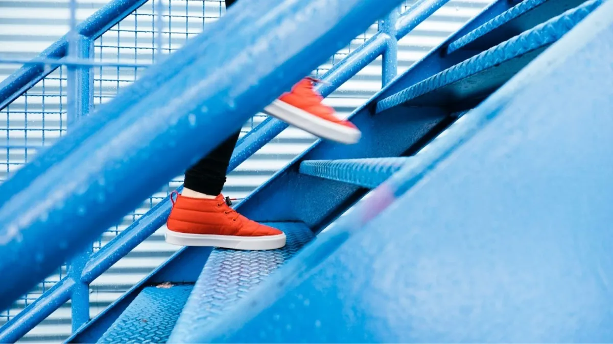 A person wearing red shoes climbing blue stairs.