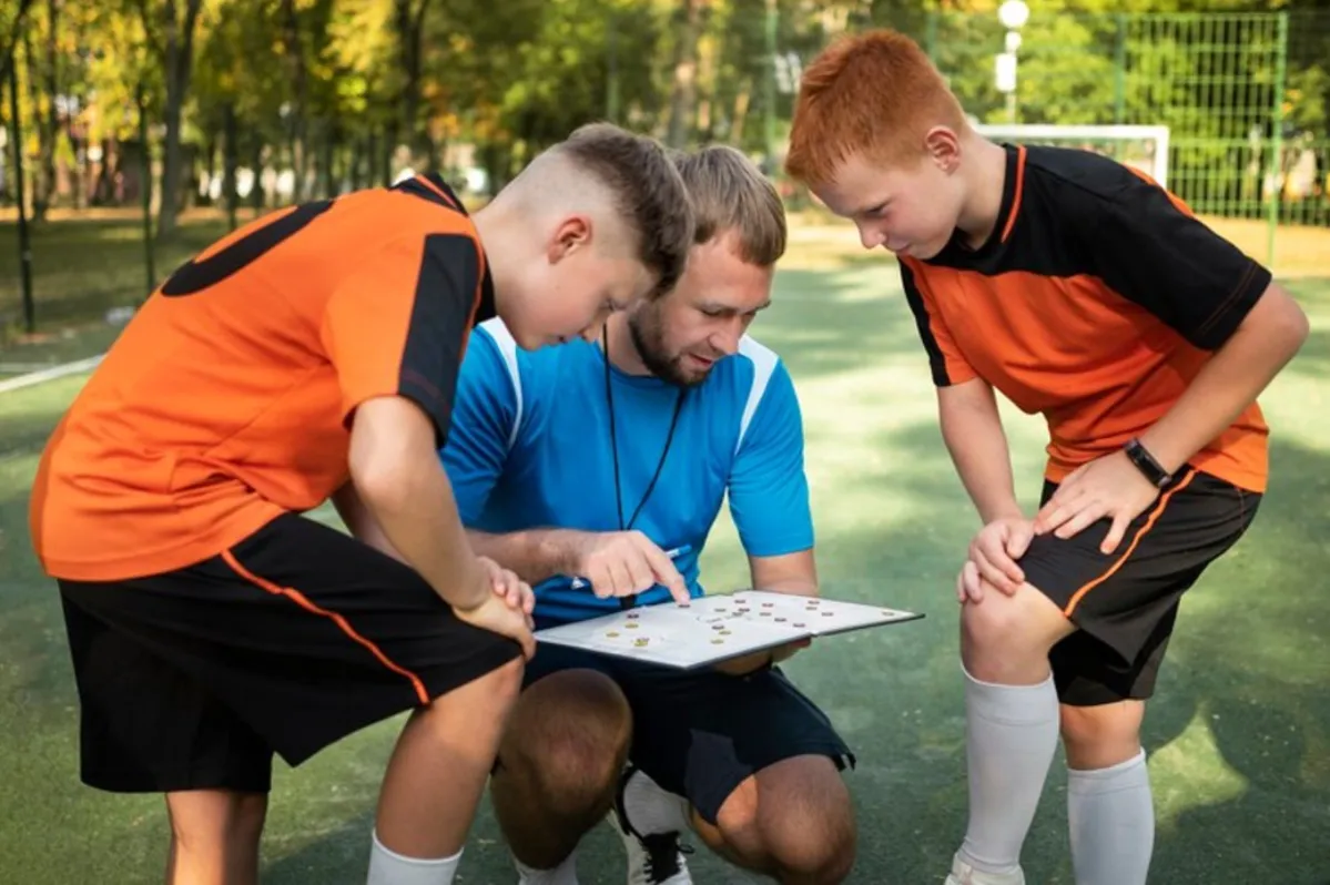 Young high school soccer coach shares tactics with two of his players