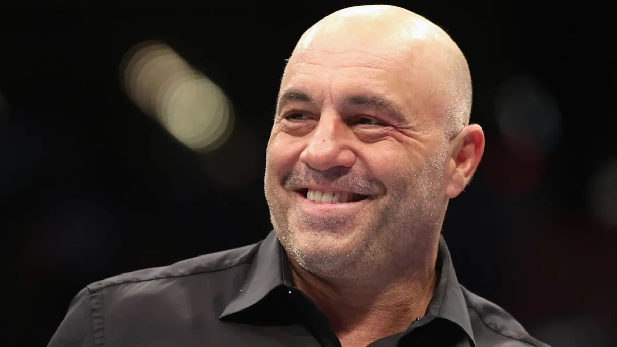 A bald man wearing a black button up shirt smiling