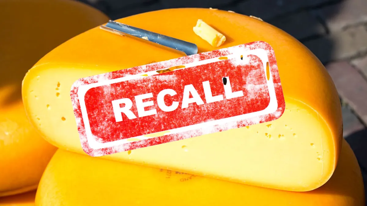 A half wheel of gouda cheese with a recall notice imposed on top of the photo