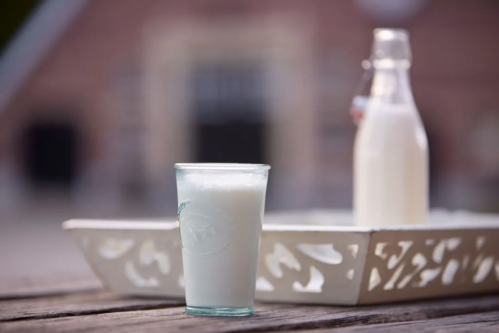 Glass of raw milk next to a bottle of raw milk
