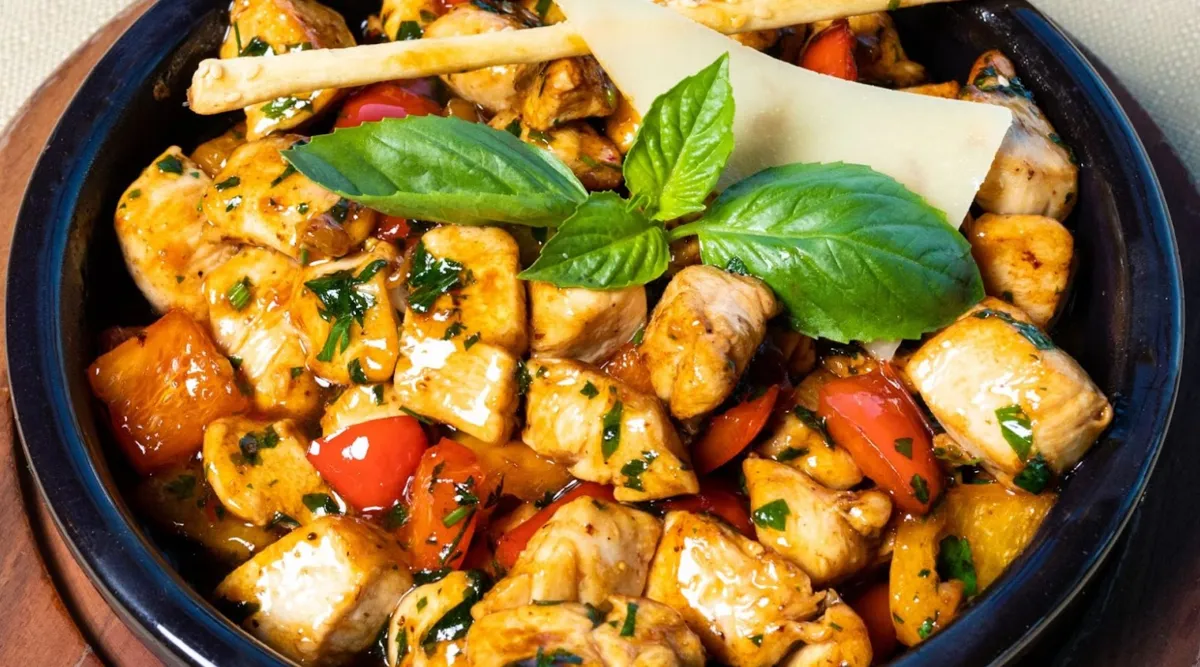 A keto diet. The food in the bowl contains meat and vegetables, including chicken and red peppers, and there is a sprig of basil on top.