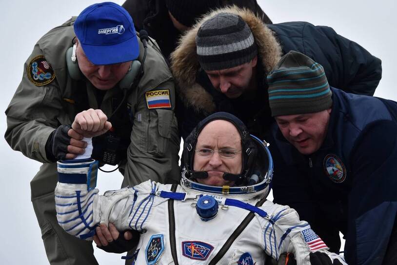 Recovery personnel assisting Scott Kelly after landing