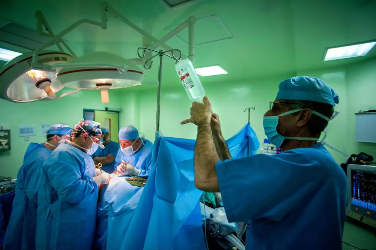 A patient undergoes surgery at a hospital surrounded by numerous doctors and nurses