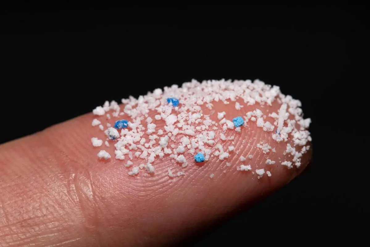 Close-up photograph of a finger with tiny microplastics on it