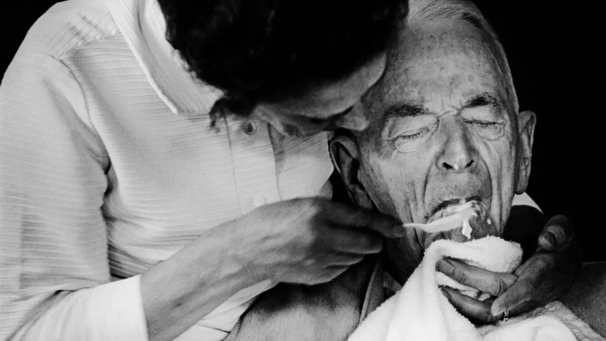 A woman feeding an old man