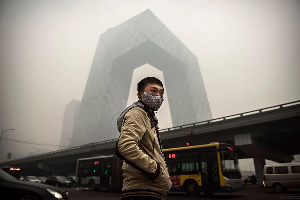 A Chinese man wears a mask as he waits to cross the road near the CCTV building during heavy smog on November 29, 2014 in Beijing, China. United States President Barack Obama and China's president Xi Jinping agreed on a plan to limit carbon emissions by their countries, which are the world's two biggest polluters, at a summit in Beijing earlier this month.