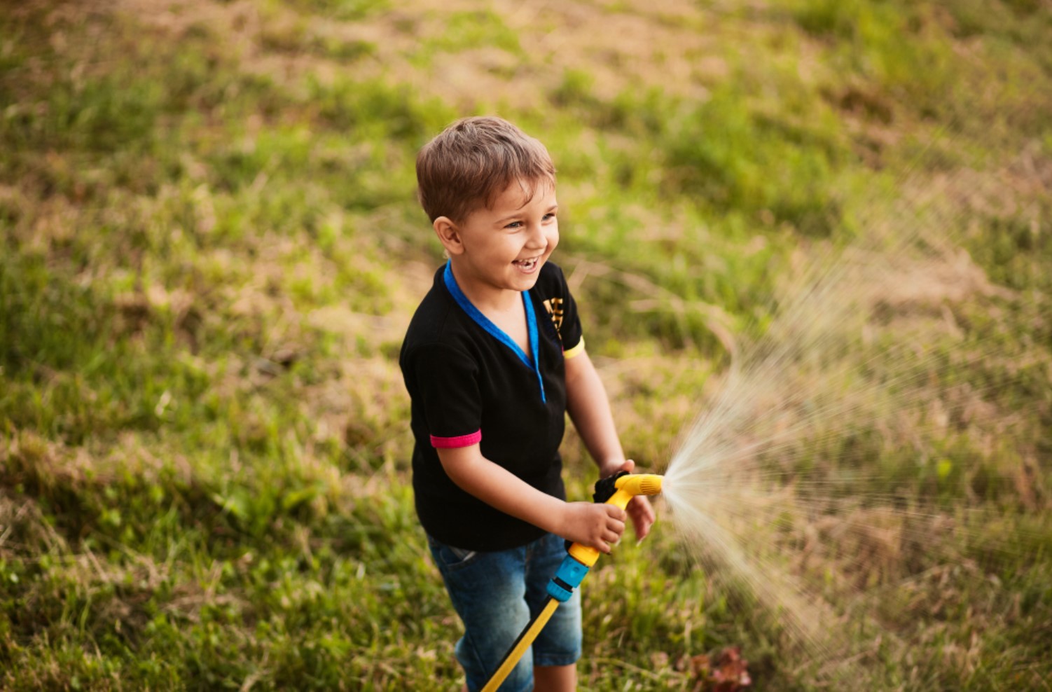 Child holding a garden hose outdoors.