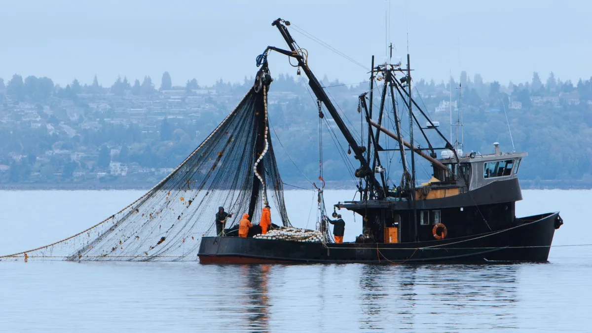 Several fishermen prepare a giant net on a commercial fishing boat