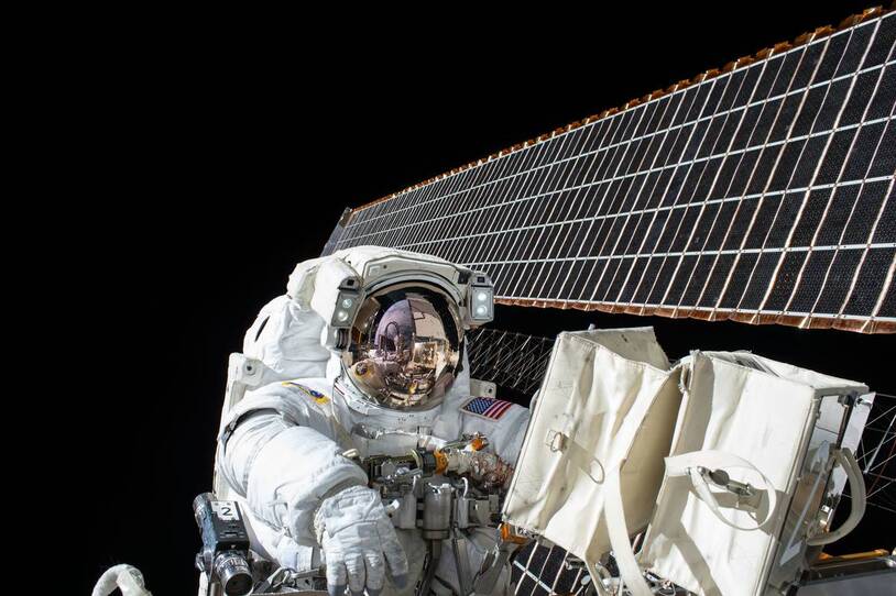 An astronaut working outside a spacecraft near a solar panel