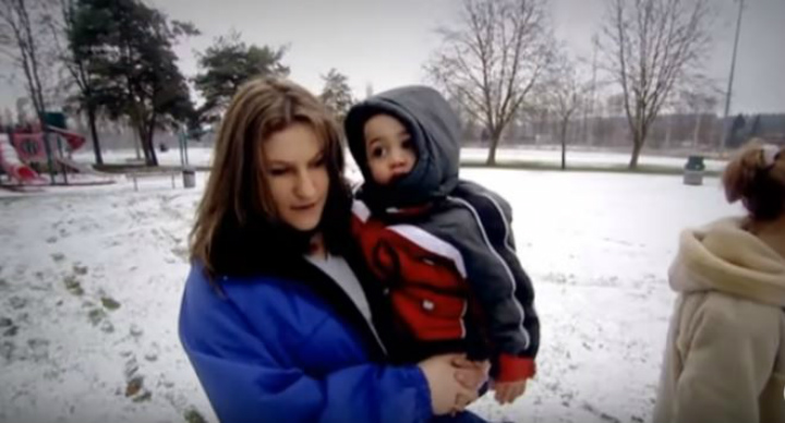 An archived documentary image of a woman holding a child outdoors