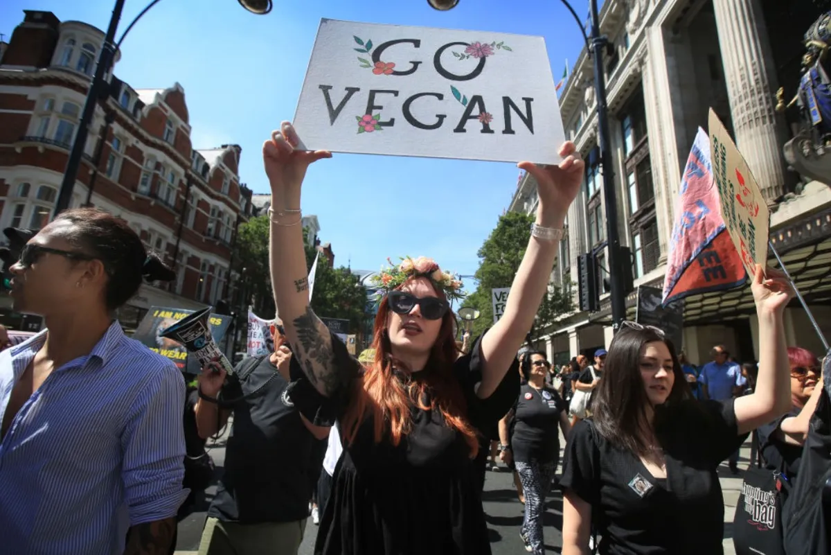 Protesters march across central London; one carries a sign saying 'Go Vegan'