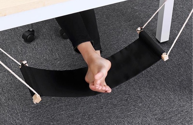 Feet resting in a suspended under-desk support