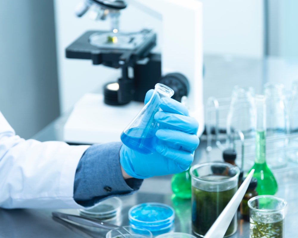 A laboratory worker beside a microscope, an illustrative photograph