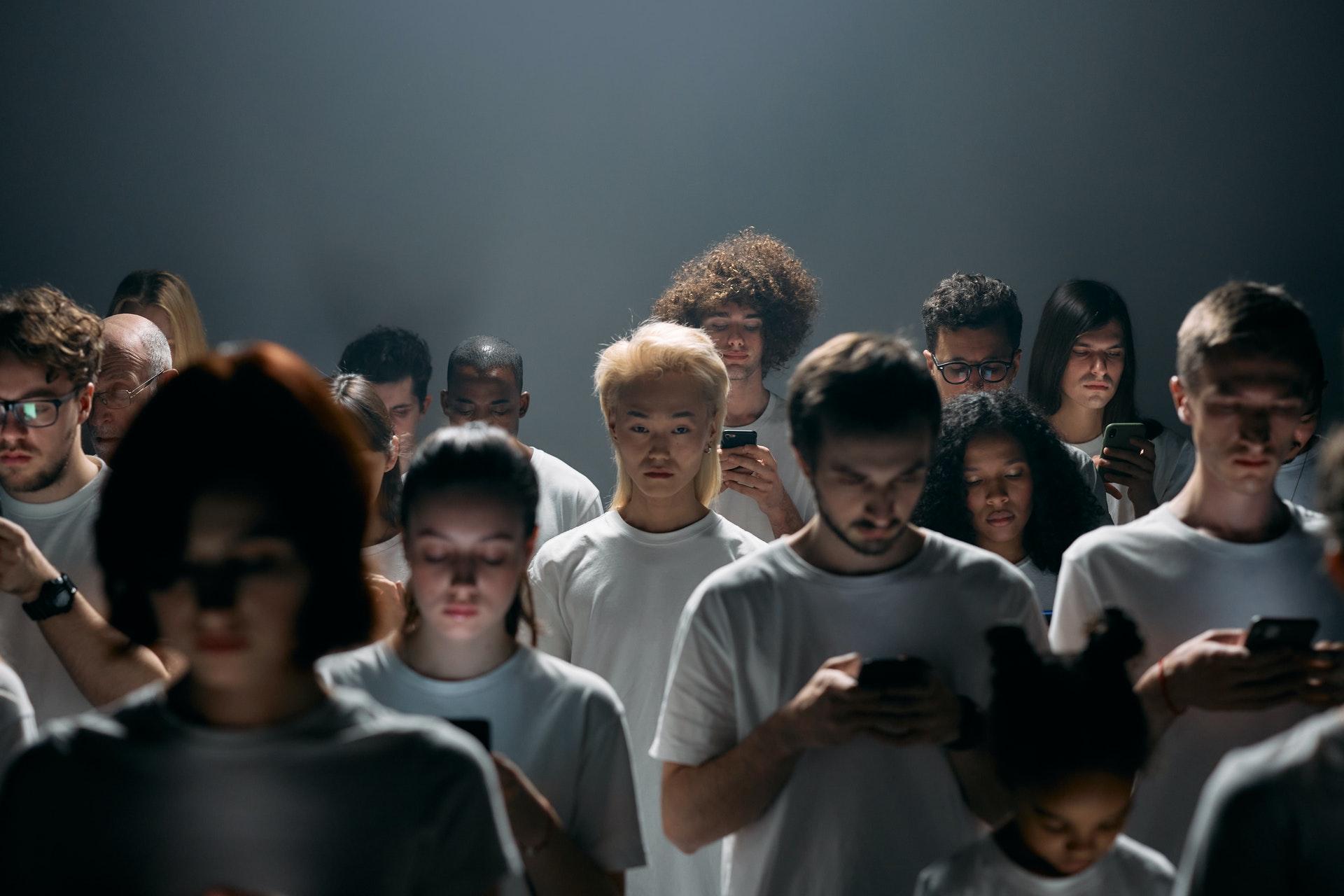 A crowd looking at mobile devices in a dark room