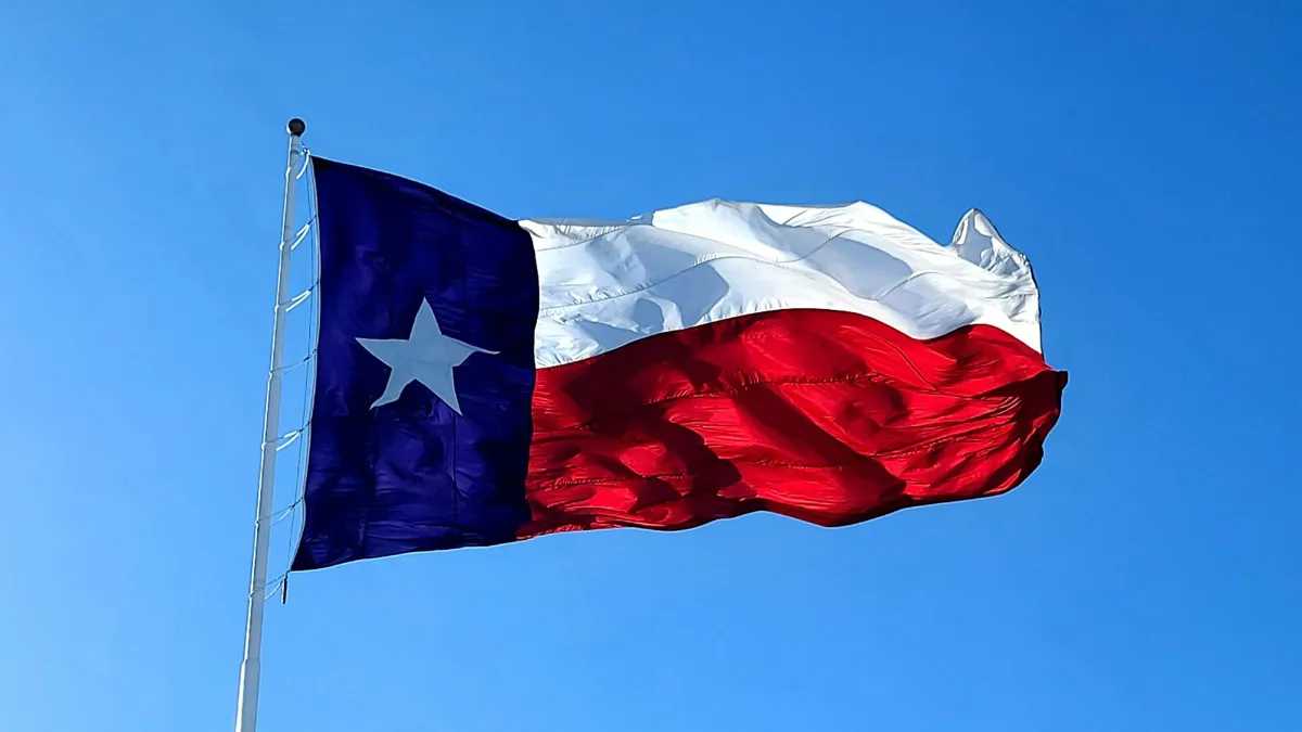 An up-close look at a Texas flag on a pole underneath a clear blue sky.