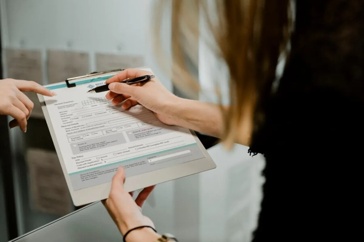 A woman applies for a job via a paper application on a clipboard
