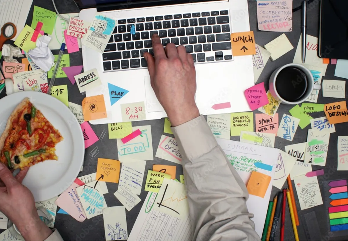Man eating pizza while working with dozens of post-it notes