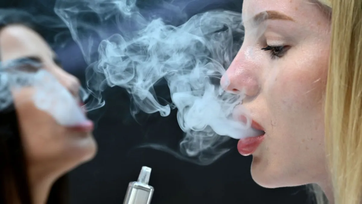 Two women vaping with large plumes of smoke