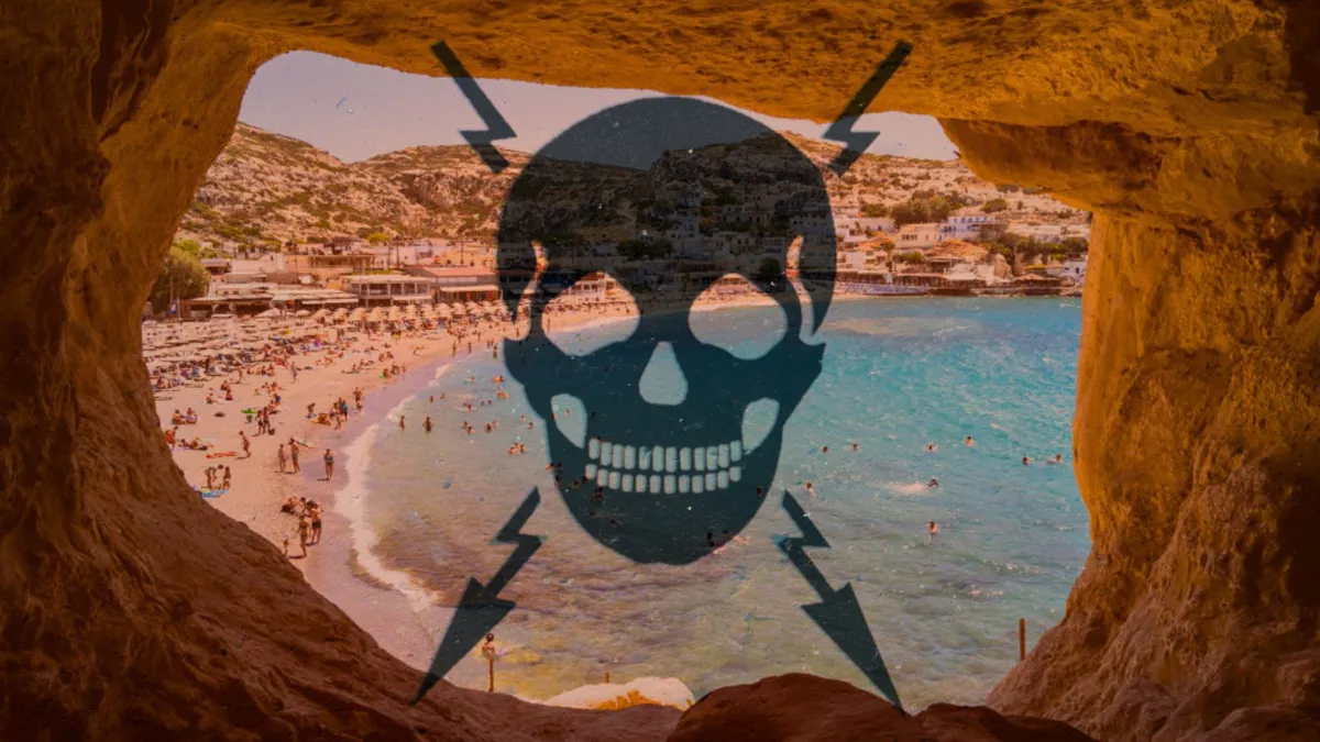 A view through a cave of a busy beach in a bay on a sunny Greek island