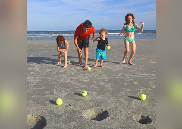 Children playing a throwing game on wet sand.