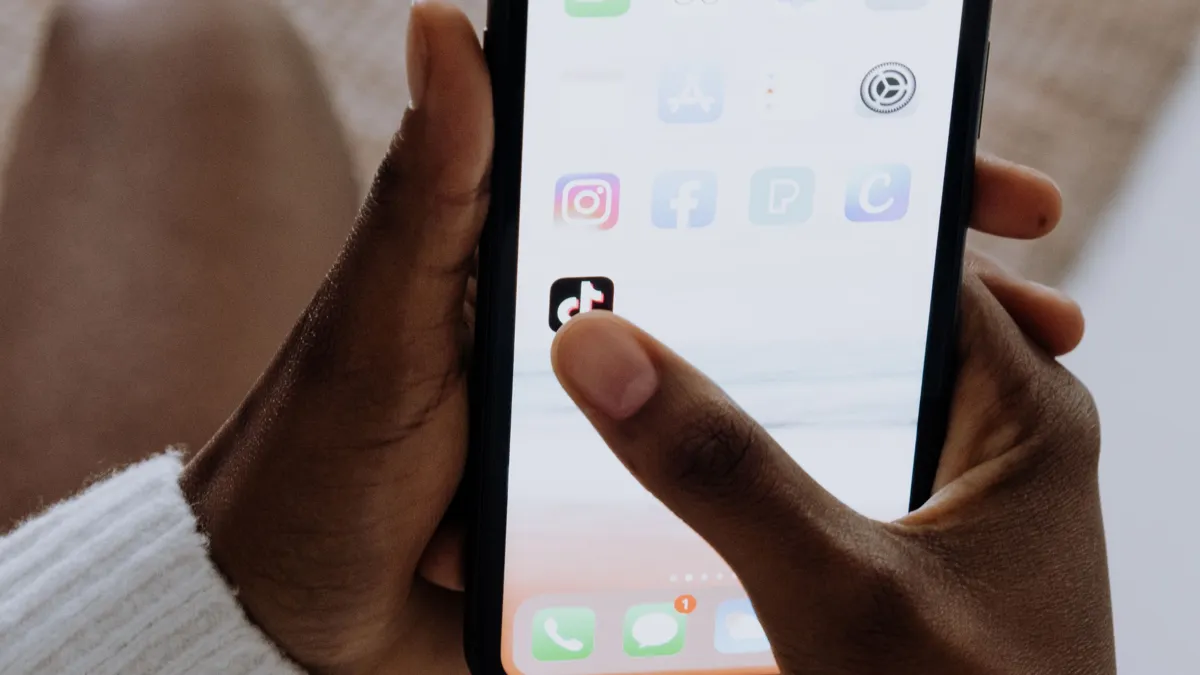 Finger navigating to TikTok app on phone
