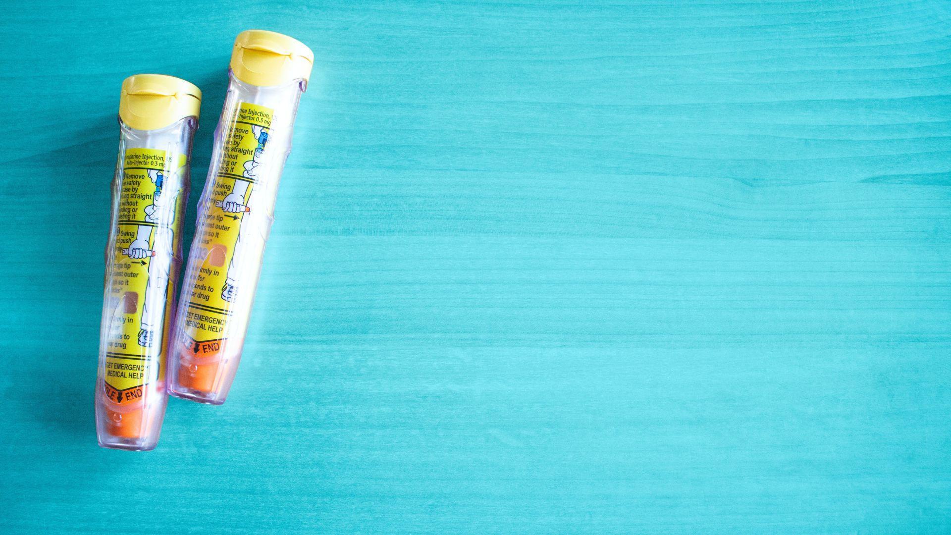 Two auto-injectors on a blue surface