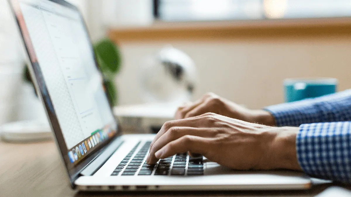 A close-up of someone’s hands working on a laptop.