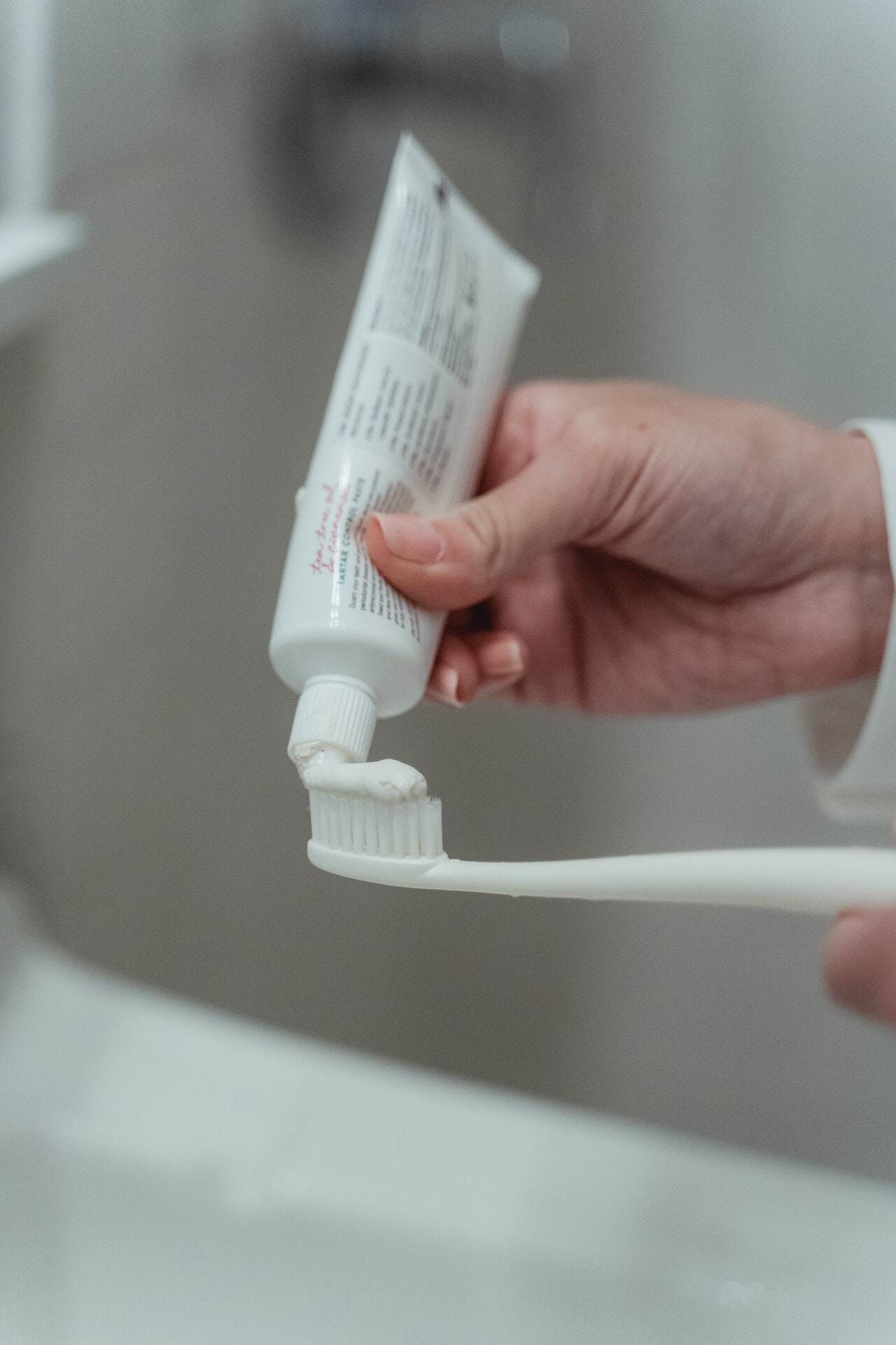 Person squeezing toothpaste onto a toothbrush