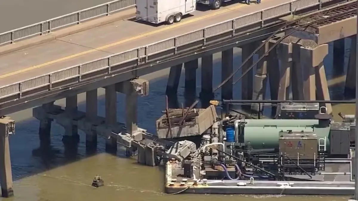 A barge collided with a pole underneath a long bridge over top muddy waters