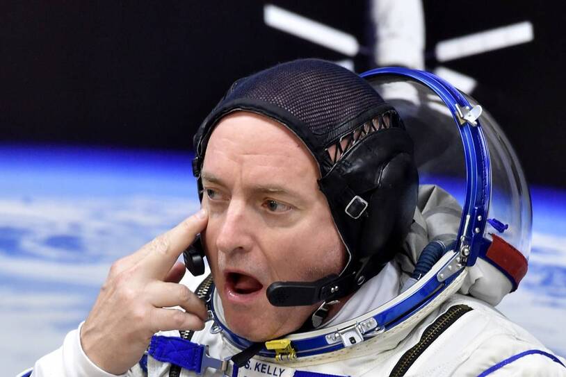 A helmeted astronaut beside a spacecraft seat