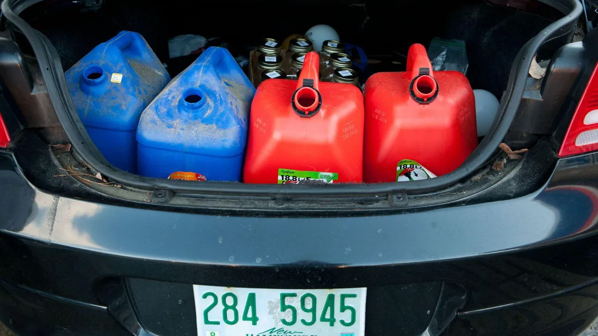 Four gas containers in the trunk of a car. Two are blue, and the other two are red.