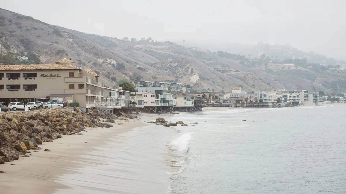 A view of a sandy beach with houses along the shore on a foggy day