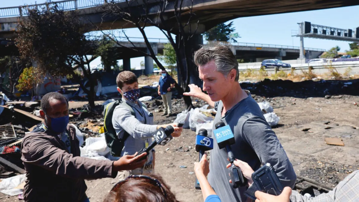 Gavin Newsom being interviewed in front of a highway